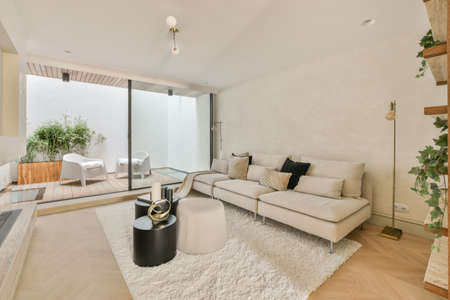 Large soft velvet couch with colorful cushions in living room with wooden parquet and kitchen island under ceiling with beamsの写真素材