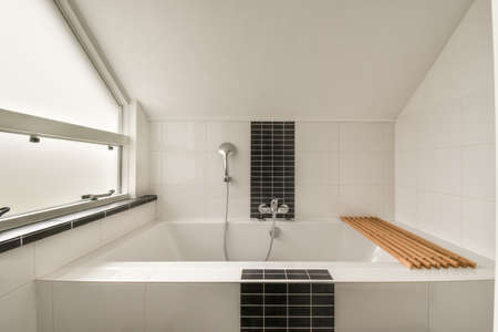 Modern home interior design of white bathroom with open bathtub and shower separated from toilet by...