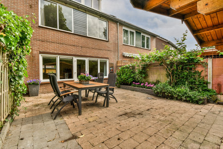 Neat paved patio with sitting area and small garden near wooden fence