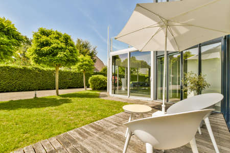 Neat paved patio with sitting area and small garden near wooden fence