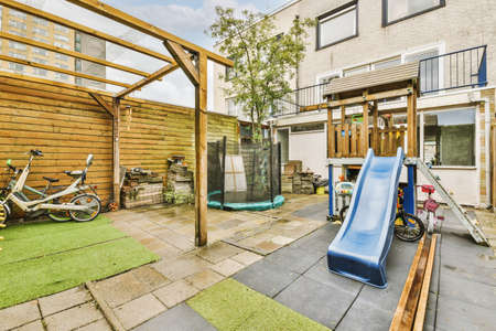 Neat paved patio with sitting area and small garden near wooden fence