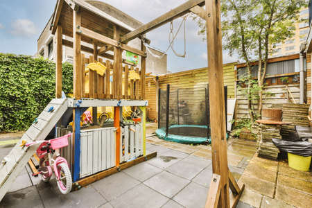 Neat paved patio with sitting area and small garden near wooden fence
