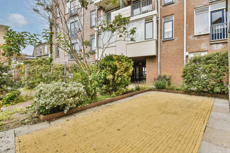 The front view of a brick building with signs,pavement and wooden doors lead to the apartment