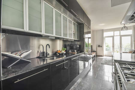 Table with chairs and flowers located near lounge area and kitchen in spacious room of contemporary...