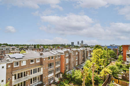 Panorama view of brick houses from an empty sidewalk street with cars, trees and lanterns