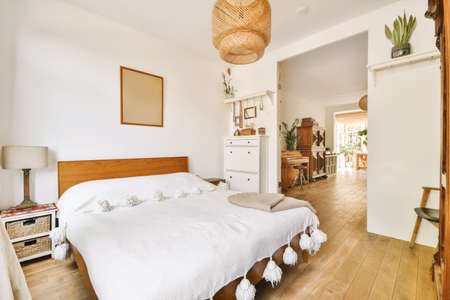 Home interior design of bedroom with bed and wooden wardrobe placed in corner near window in modern...
