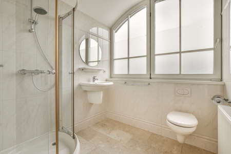 Sinks with mirrors and clean bathtub located near shower box with glass door in modern bathroom with white tiled wallsの写真素材