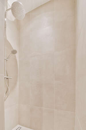 Shower faucets attached to tiled wall near glass partition and ornamental curtail in washroom at...