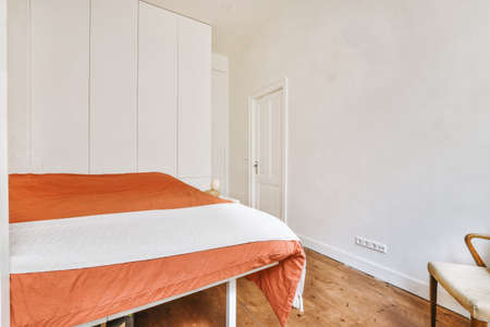 Home interior design of bedroom with bed and wooden wardrobe placed in corner near window in modern apartmentの写真素材