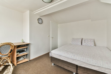 Comfortable bed covered with checkered blanket and located in light bedroom of modern apartmentの写真素材