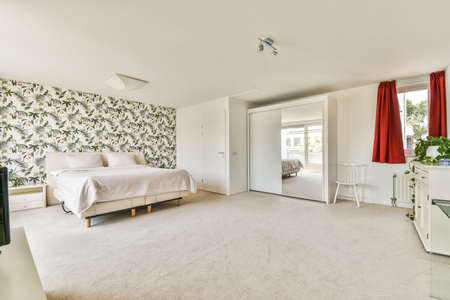 Comfortable bed and soft carpet in spacious bedroom with interior in minimal styleの写真素材