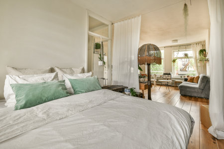 Retro bedside table and lamp located near comfortable bed and shelf with window in modern bedroomの写真素材