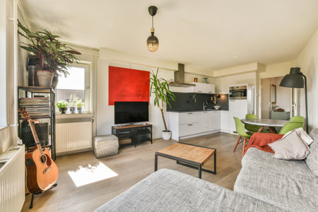 Table with chairs located near lounge area and kitchen in spacious room of contemporary apartment