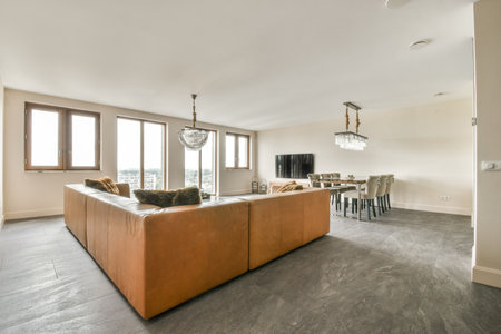 Table with chairs and TV located near lounge area and kitchen in spacious room of contemporary...