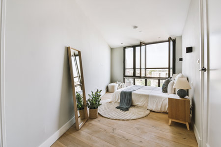 Home interior design of bedroom with bed and wooden wardrobe placed in corner near window in modern...