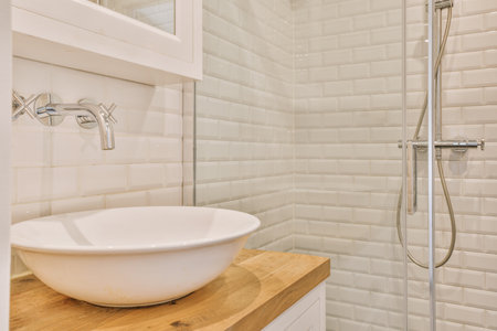 Flush toilet and shower cabin with glass partition and curtain located near sink and shelf with...