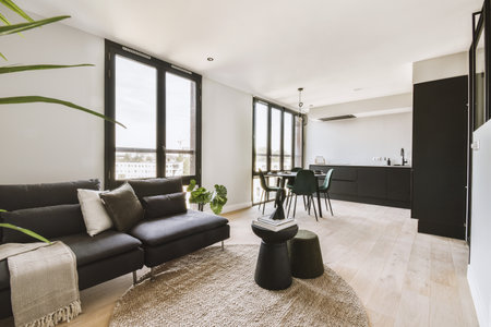 Large corner sofa with soft cushions located under elegant chandelier near electric fireplace in light living room near kitchenの写真素材