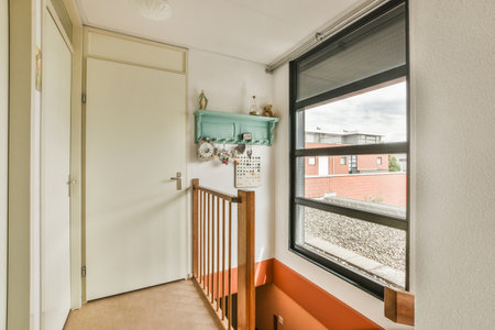 Interior of narrow corridor with stairway and window in daylight