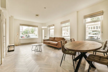 Table with chairs located near lounge area and kitchen in spacious room of contemporary apartment