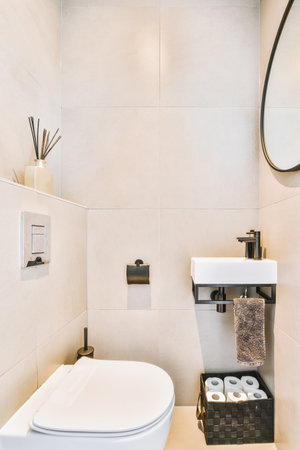 Interior of narrow restroom with sink and wall hung toilet with white walls and checkered floorの写真素材