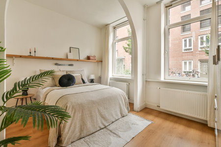 Comfortable bed with white bedclothes and bedside table with lamp placed in light bedroom at home