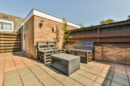 Neat powerful patio with sitting area and small garden near wooden fence