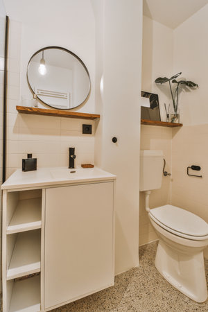 Flush toilet located between sink and shower in small tiled bathroom of contemporary apartment