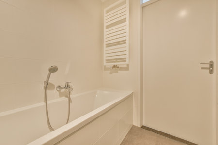 Modern flush toilet and ceramic sink installed on white tiled walls near mirror and shower box in...