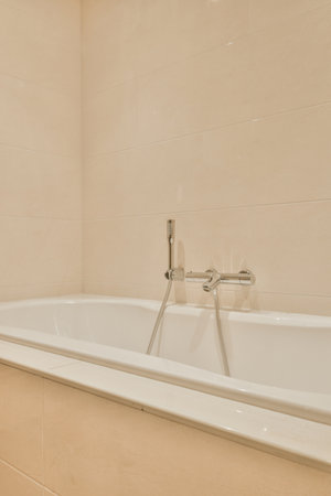 Modern home interior design of white bathroom with open bathtub and shower separated from toilet by partition wallの写真素材