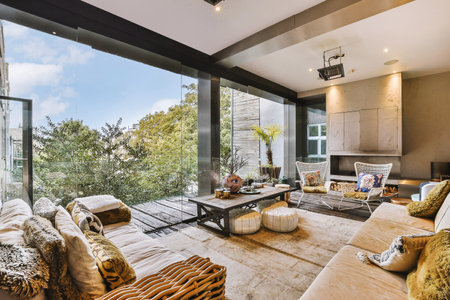 Stylish home interior design of spacious living room with large windows and white walls furnished with comfy couch and table on carpet on parquet floorの写真素材