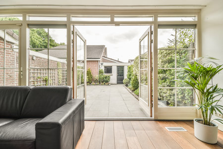Wooden table with chairs and vase located near comfortable couch against light walls with...