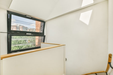 White hallway with wooden stairway leading to second floor of modern luxury apartment with...