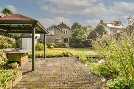 Neat paved patio with sitting area and small garden near wooden fence
