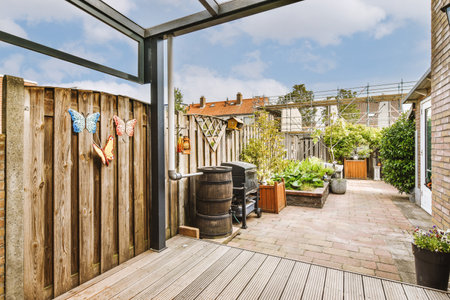 Neat paved patio with sitting area and small garden near wooden fence