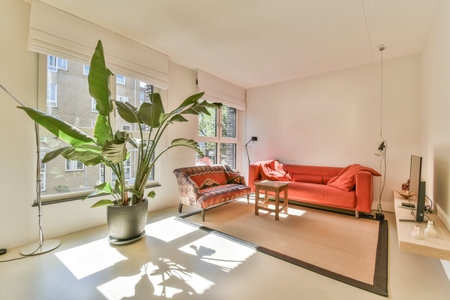 Table with chairs and flowers located near lounge area and kitchen in spacious room of contemporary...