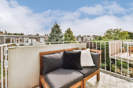 Narrow brick balcony with metal railings, wooden chair and door