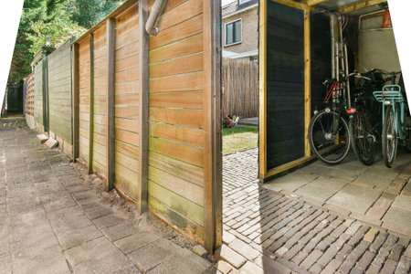 Spacious garage with bicycles and storage furniture near small gardenの写真素材