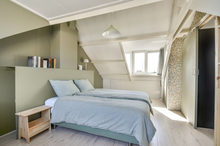Comfortable bed placed in modern minimalist style mansard bedroom with windows