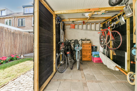 Spacious garage with bicycles and storage furniture near small gardenの写真素材