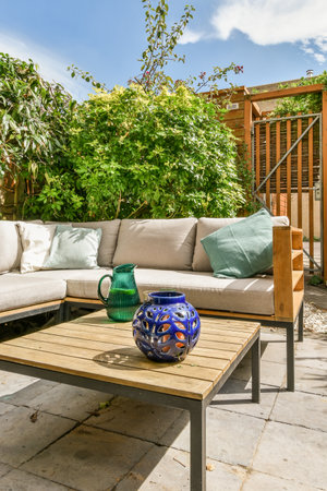 Neat powerful patio with sitting area and small garden near wooden fence