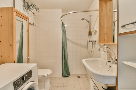 Flush toilet located between sink and shower in small tiled bathroom of contemporary apartment