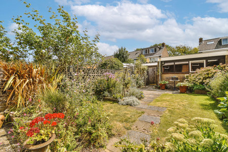 Neat paved patio with sitting area and small garden near wooden fence