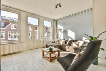 Interior of living room with comfortable sofa and armchairs around table with wooden stairway...