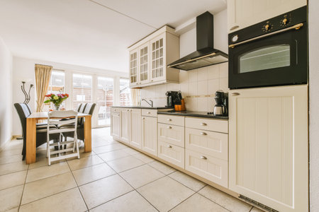 a kitchen with white cabinets and black appliances on the counter tops, along with a dining area in...