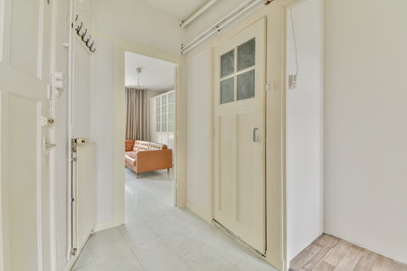 an empty hallway with white walls and wooden doors, leading to the living room on the left is a sofa