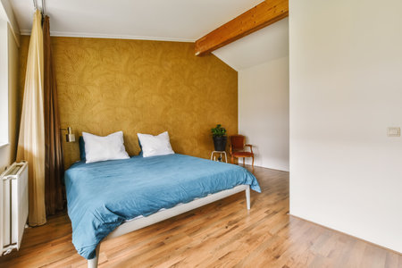 a bed in a room with wood flooring and yellow wallpaper on the walls behind it is a window