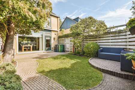 Neat paved patio with sitting area and small garden near wooden fence