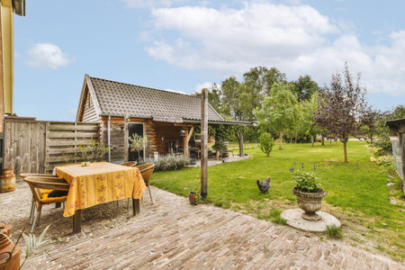 Neat paved patio with sitting area and small garden near wooden fence