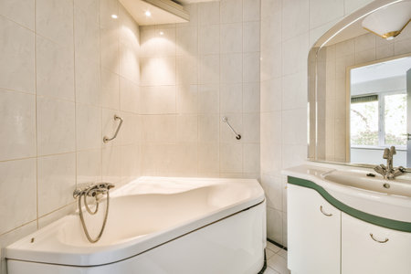 a bathroom with white tiles and green trim around the tub, sink, and mirror in its corner