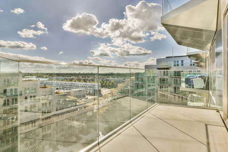 an outside area with buildings and clouds in the sky as seen from a glass railing on a balcony...